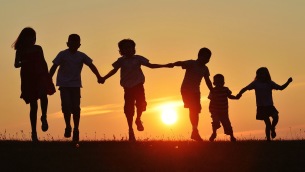 Happy children silhouettes on summer meadow running and jumping