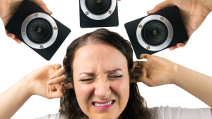 46533331 - woman with hands in the ears disturbed by loud noise of the speakers